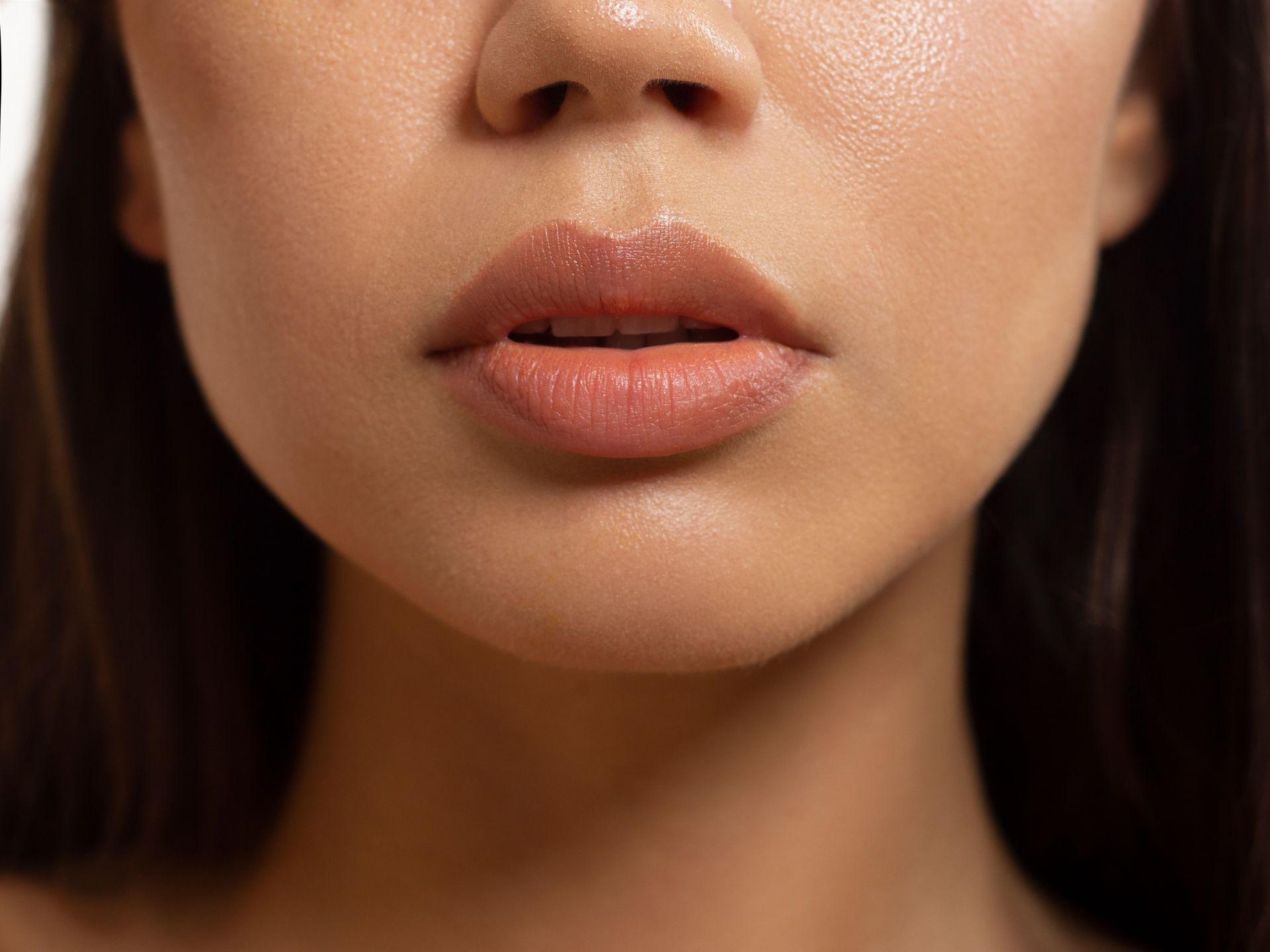 Close-up of a person's face, focusing on their lips. The lips are lightly colored with a glossy finish.