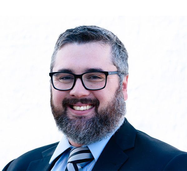 A man with a beard and glasses is smiling for the camera