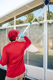 A man is spraying a brick building with a sprayer.