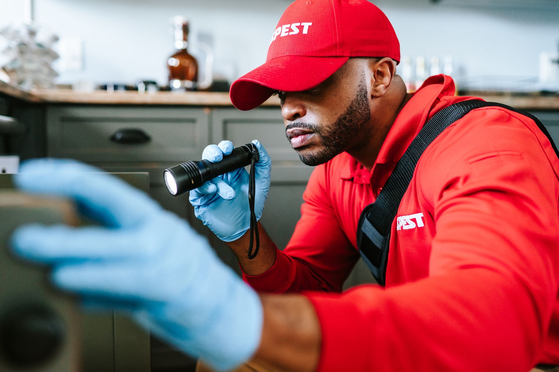 A man in a red shirt and blue hat is kneeling down in front of a house.