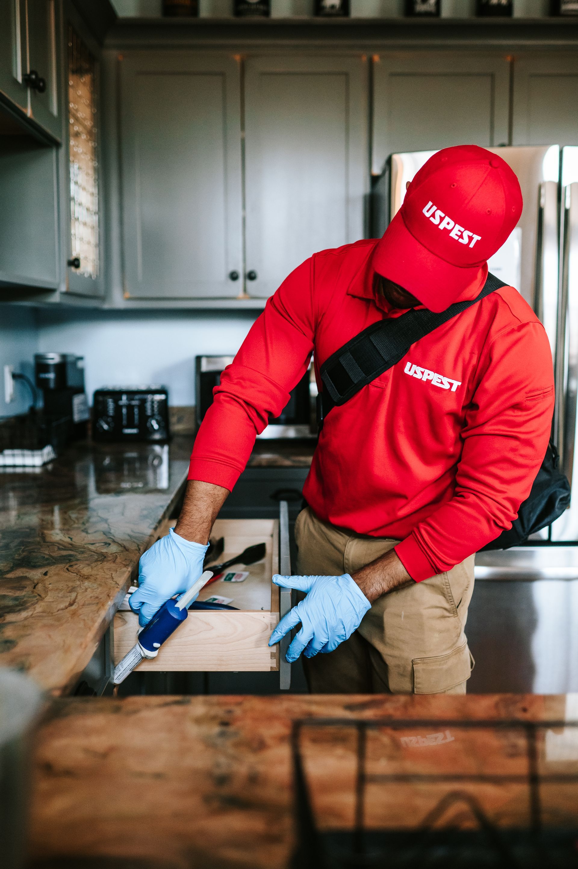 A man is spraying a brick building with a sprayer.