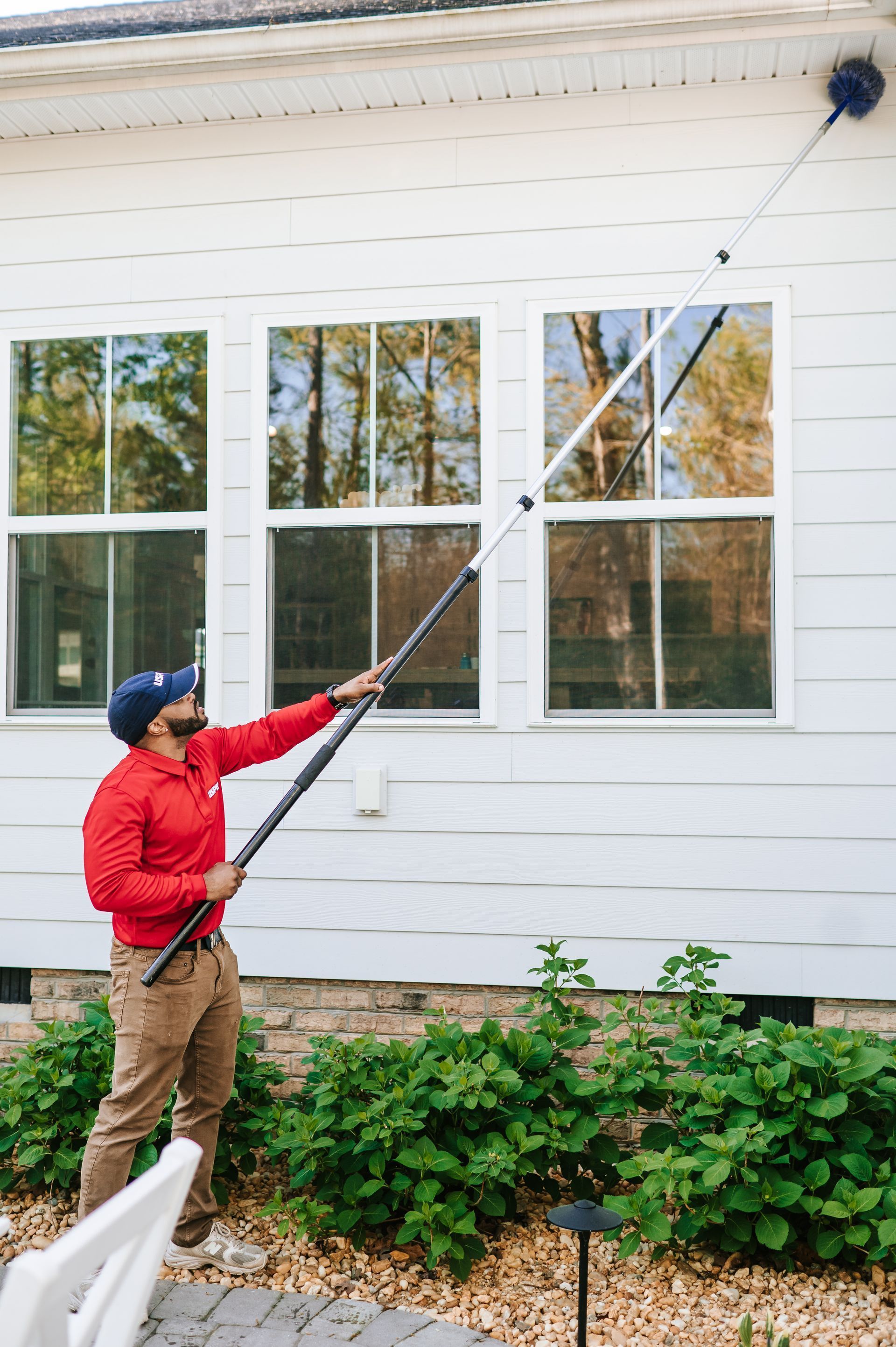 A man is spraying a brick building with a sprayer.