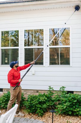 A man is spraying a brick building with a sprayer.