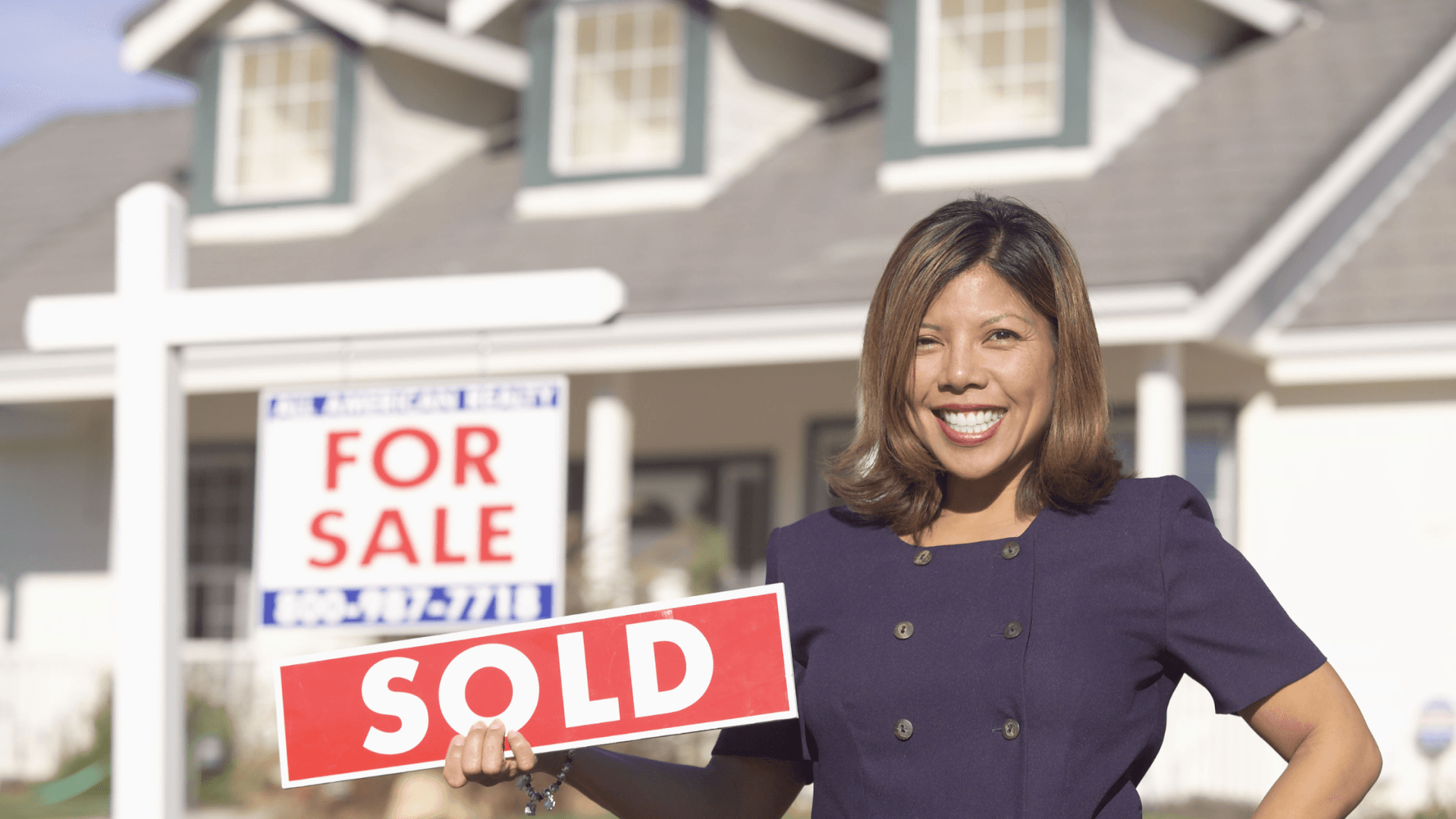 Real Estate Agent sitting in front of a sold sign