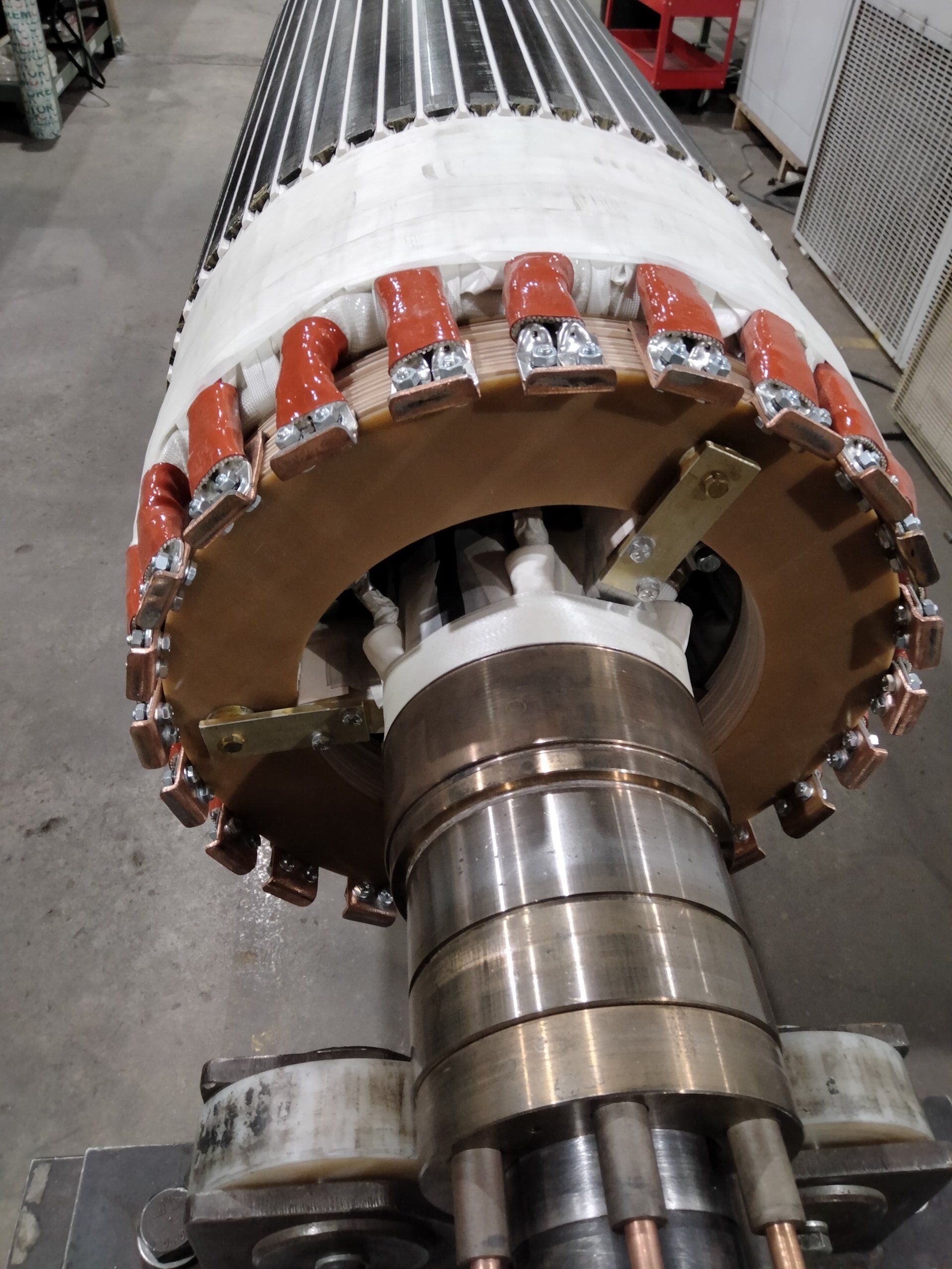Primer plano de un rotor de motor eléctrico de gran tamaño con bobinados y aislamiento de cobre.