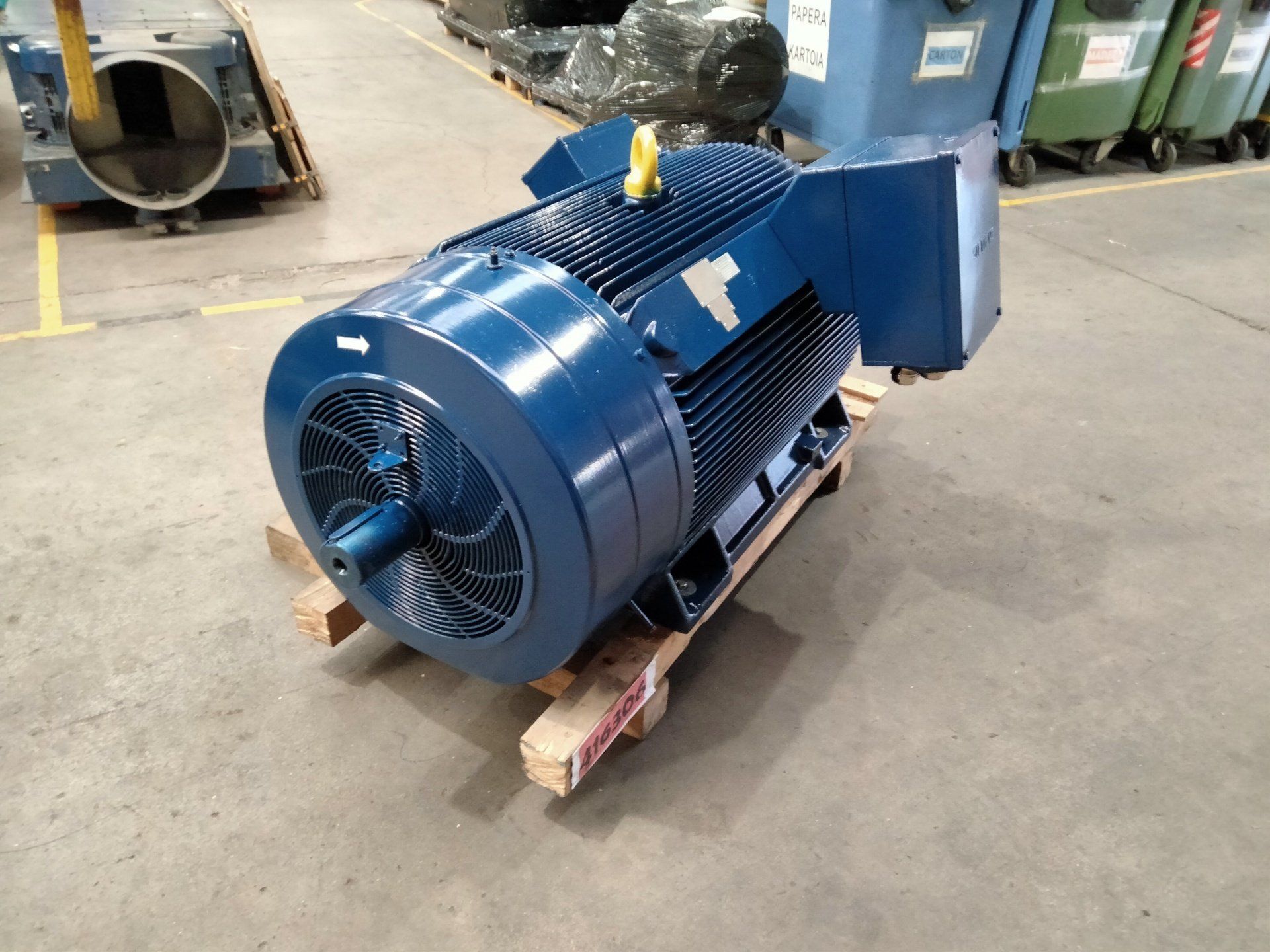 Motor eléctrico industrial azul sobre un palé en un almacén.