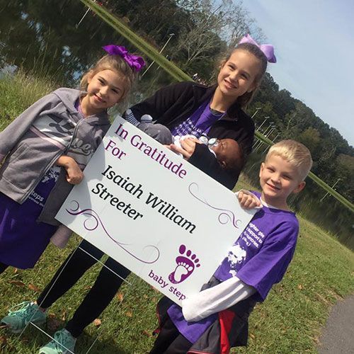 Three children holding a sign that reads