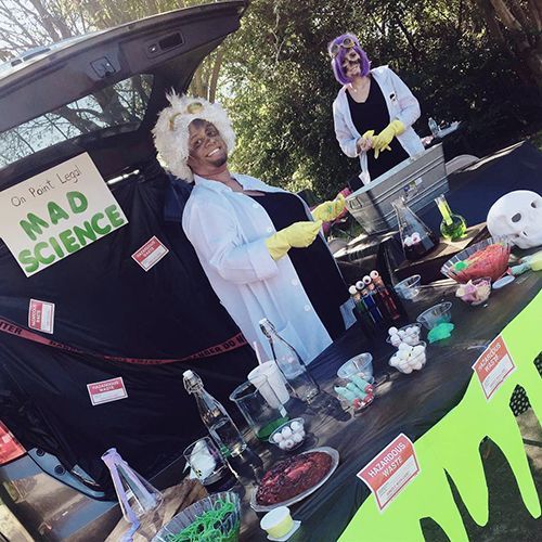 Two people in lab coats and wigs at a 