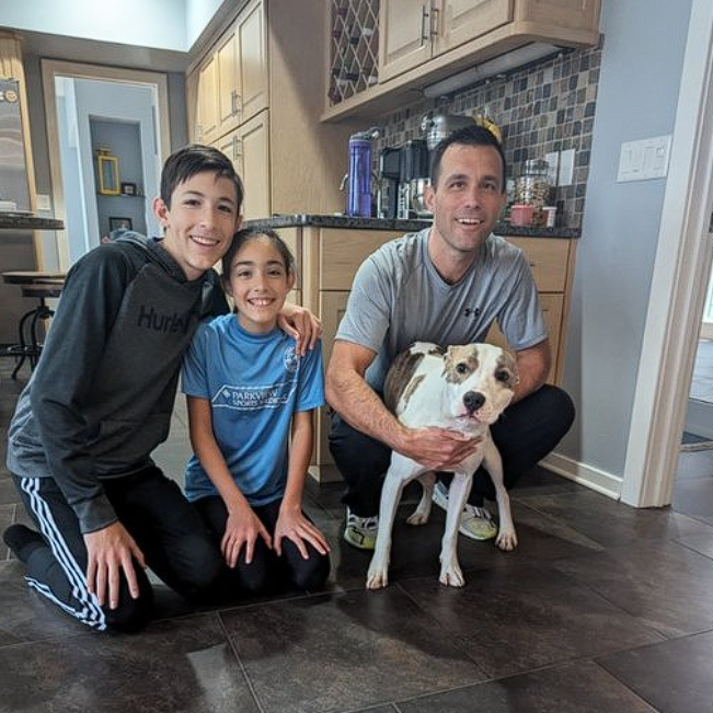 A man and two children are posing for a picture with a dog.