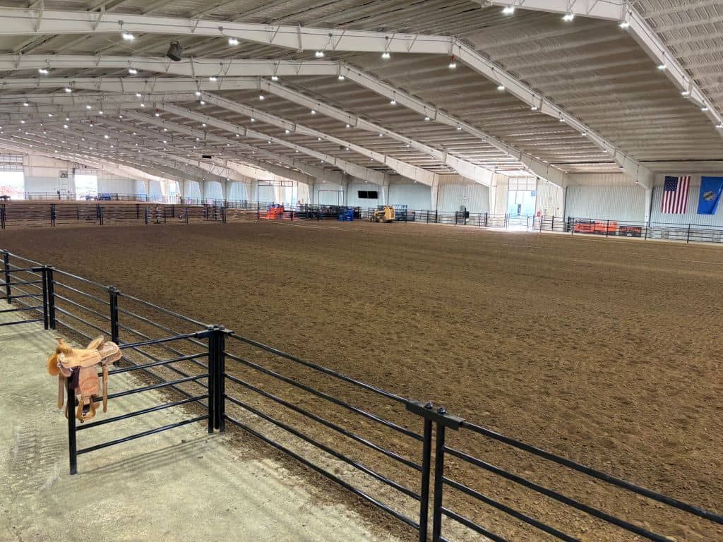 A large indoor arena with a fence and a flag on the wall.
