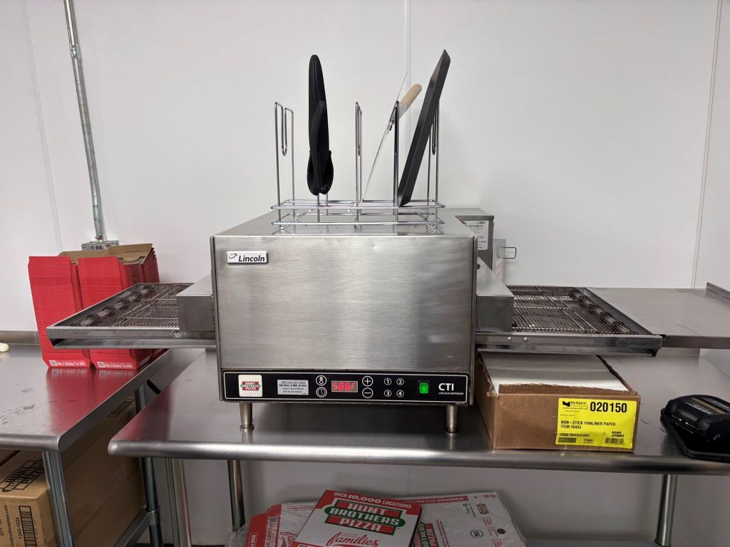 A pizza oven is sitting on a stainless steel table