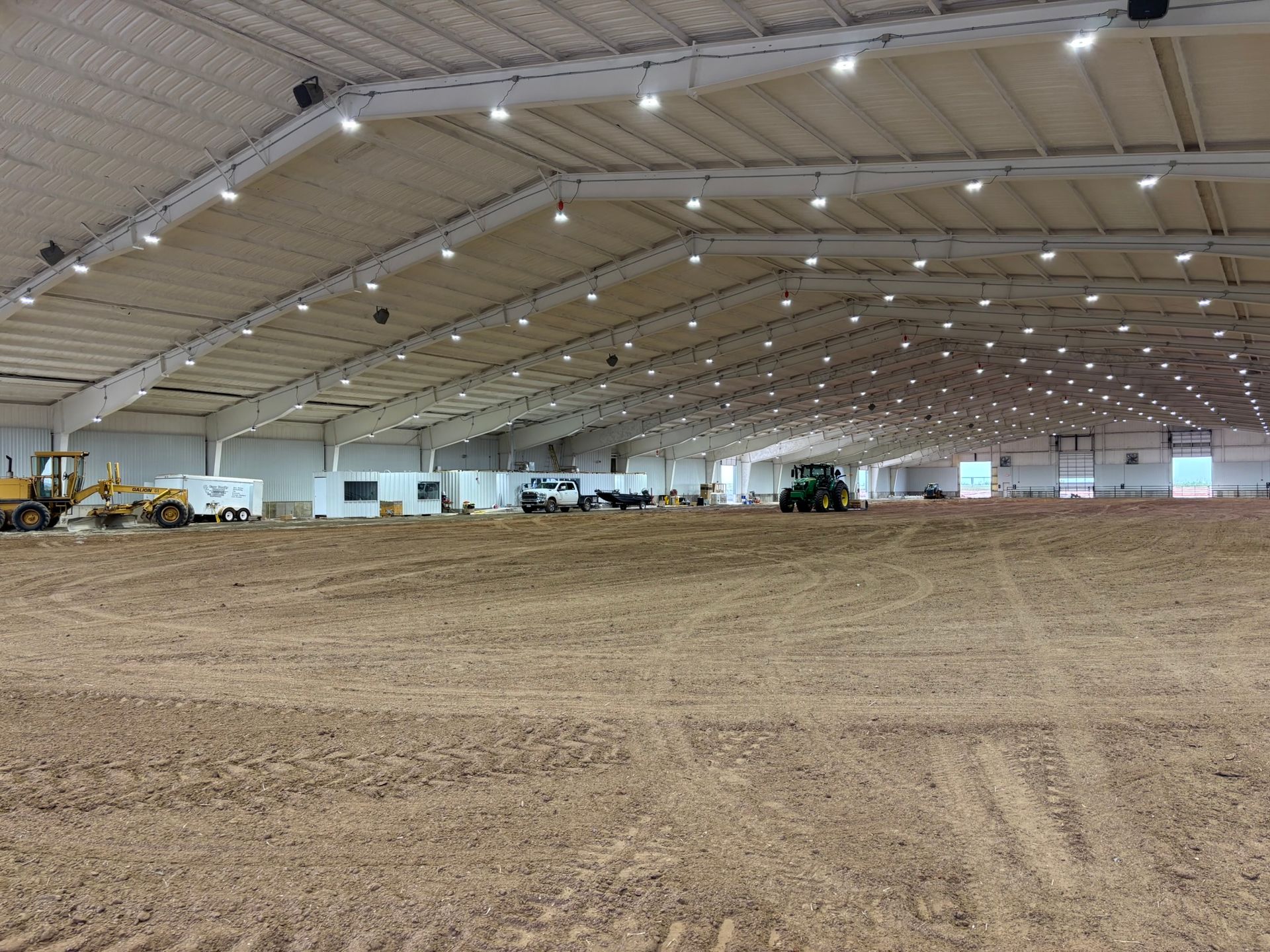 A large roping arena building with a lot of dirt inside of it