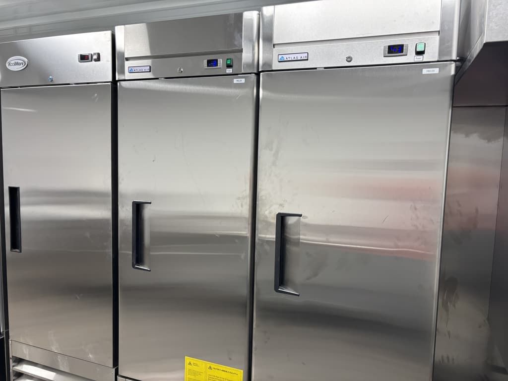 A row of stainless steel refrigerators in a kitchen