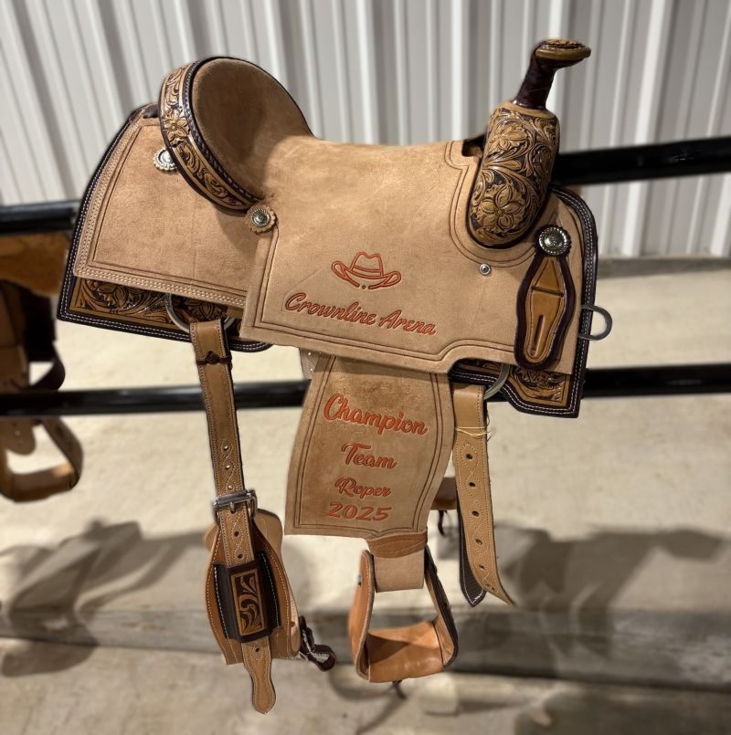 Tan leather rodeo saddle with decorative carving and 