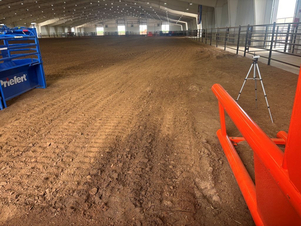 An empty rodeo arena with a tripod in the foreground.