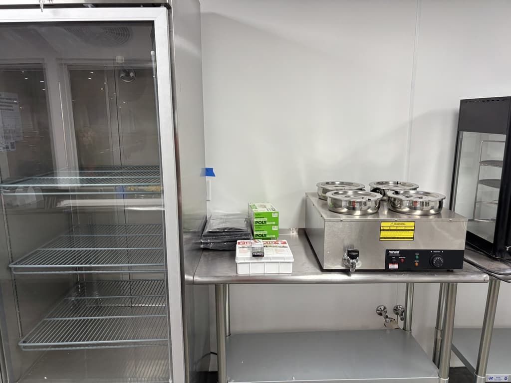 A kitchen with a refrigerator and a table with a machine on it.