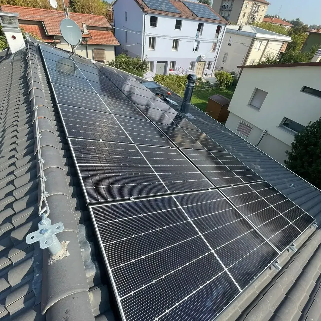 Pannelli solari su un tetto di tegole grigie. Edifici e cielo sullo sfondo.