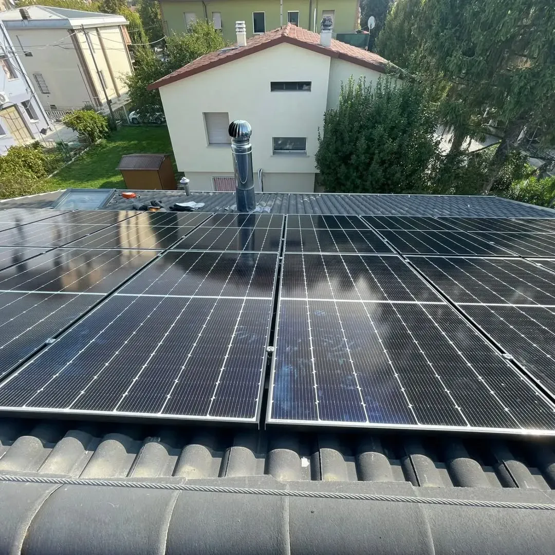 Pannelli solari installati su un tetto con camino.