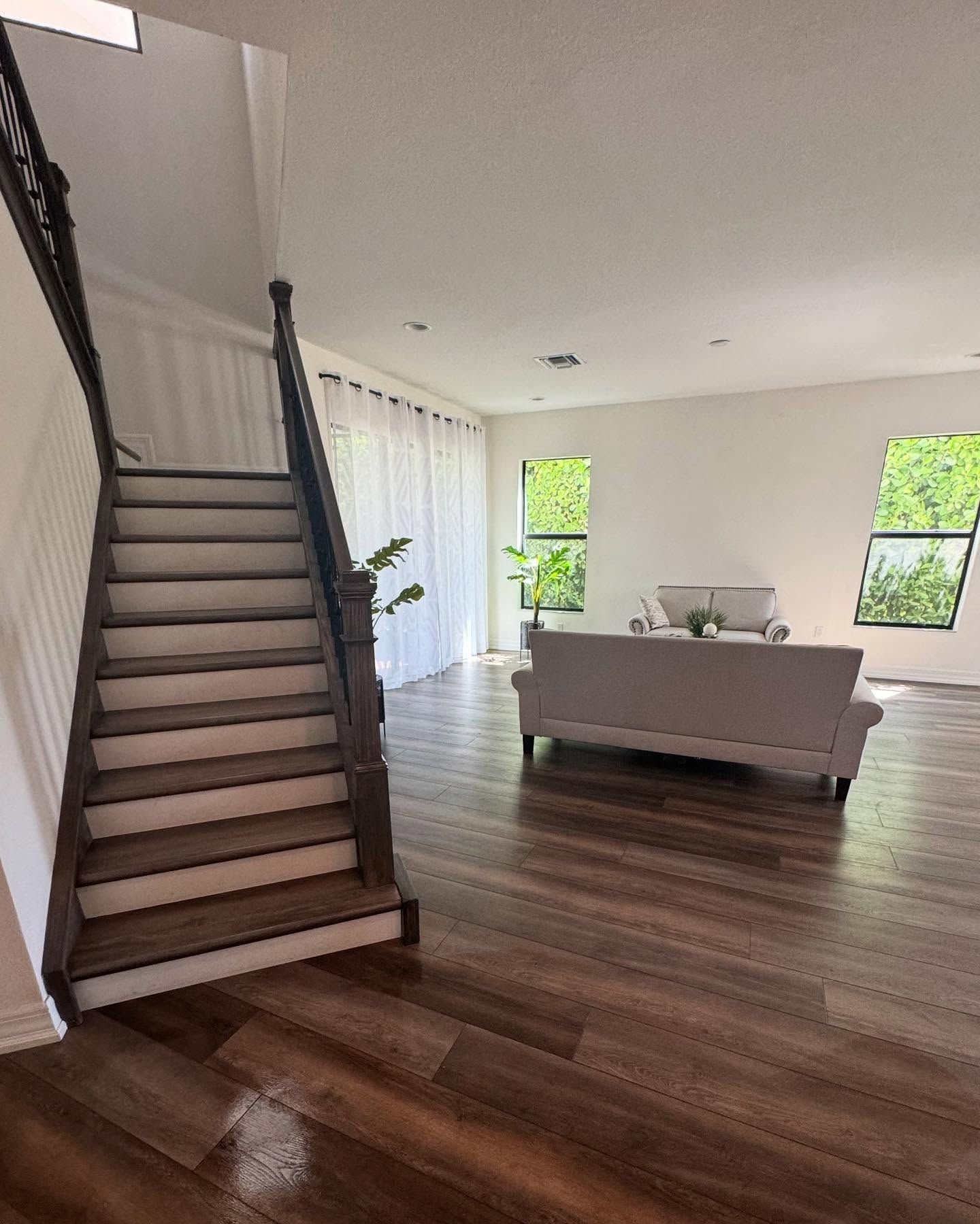 A living room with hardwood floors and stairs leading up to the second floor.