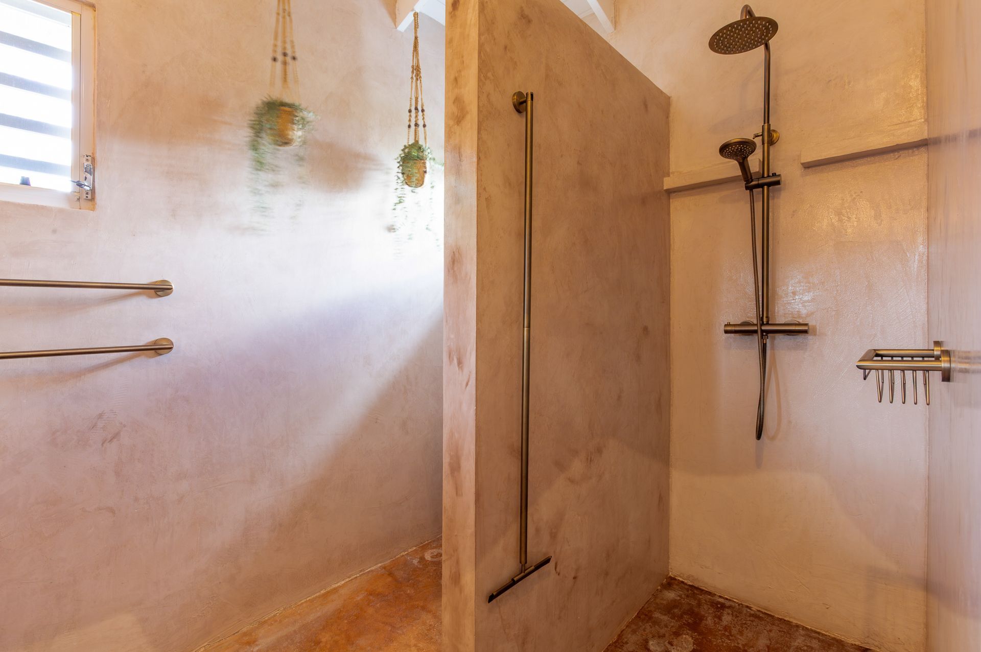 Douche met betonnen wanden en armaturen, inclusief een douchekop en handdoekrekken.