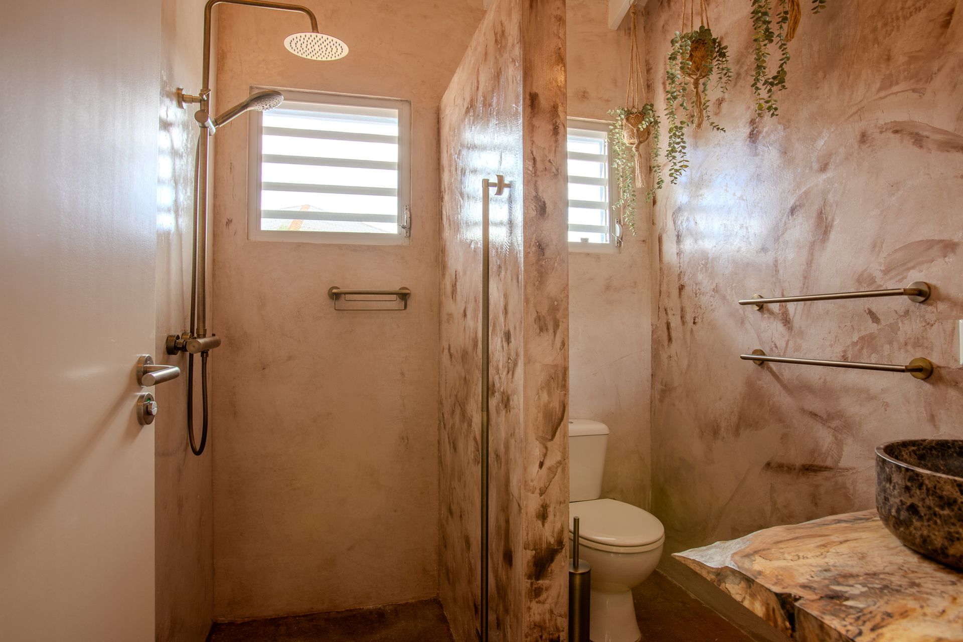 Rustieke badkamer met douche, toilet en decoratieve wanden. Beige en bruine tinten.