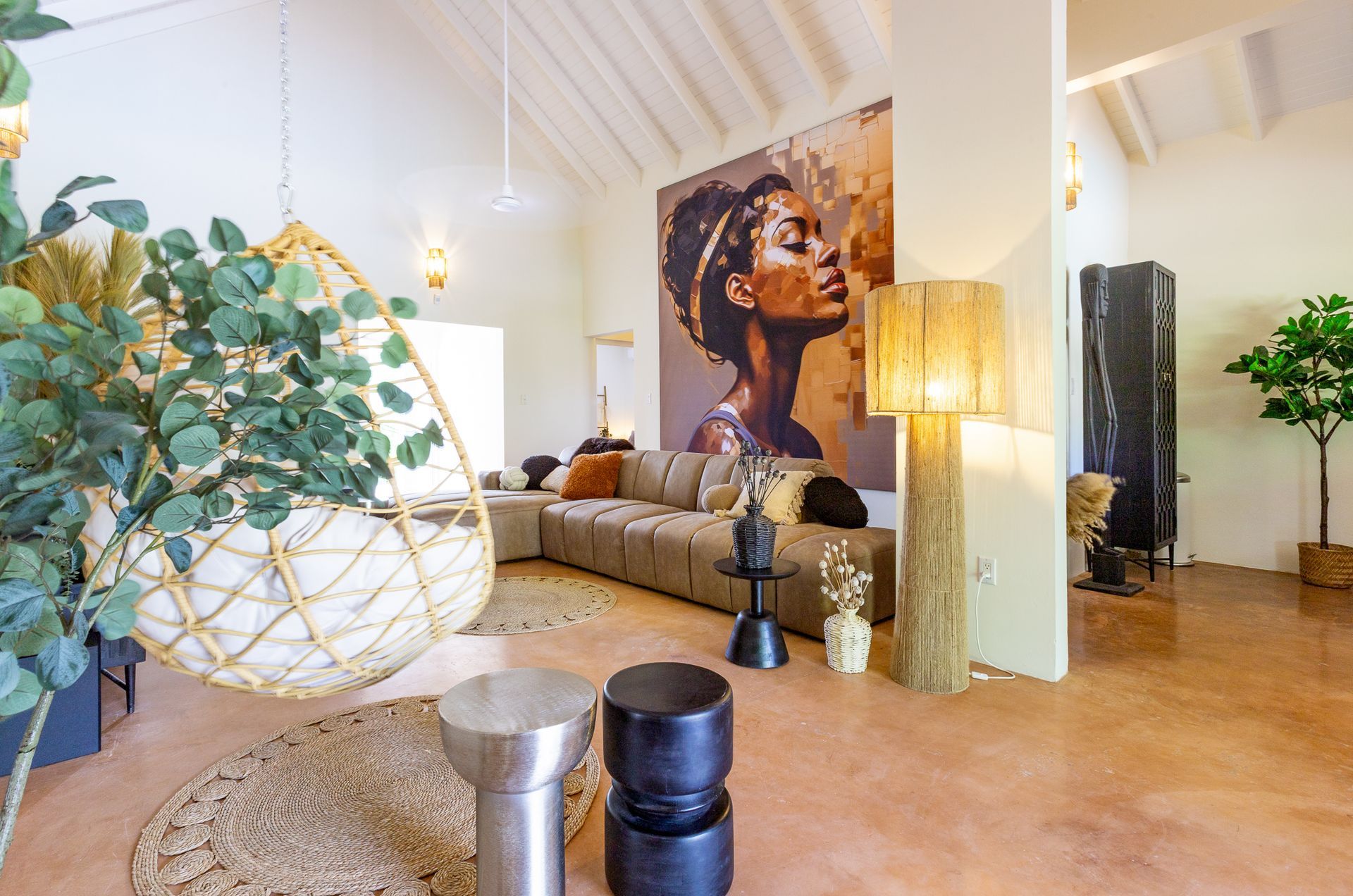 Woonkamer met kunst, een hangstoel, een vloerkleed met structuur en een grote staande lamp.