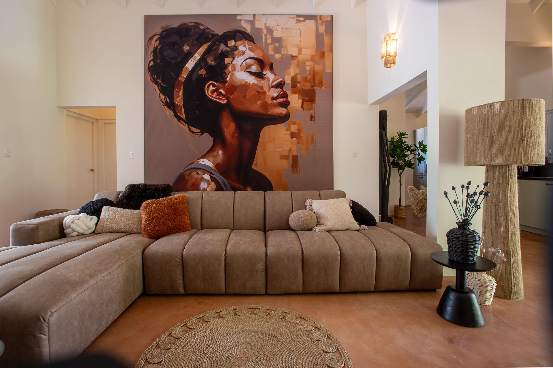 Woonkamer met een groot portret boven een bruine hoekbank, een staande lamp en een rond vloerkleed.