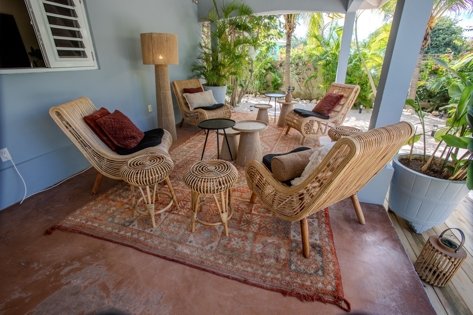 Een zitgedeelte buiten met rotan stoelen en een vloerkleed