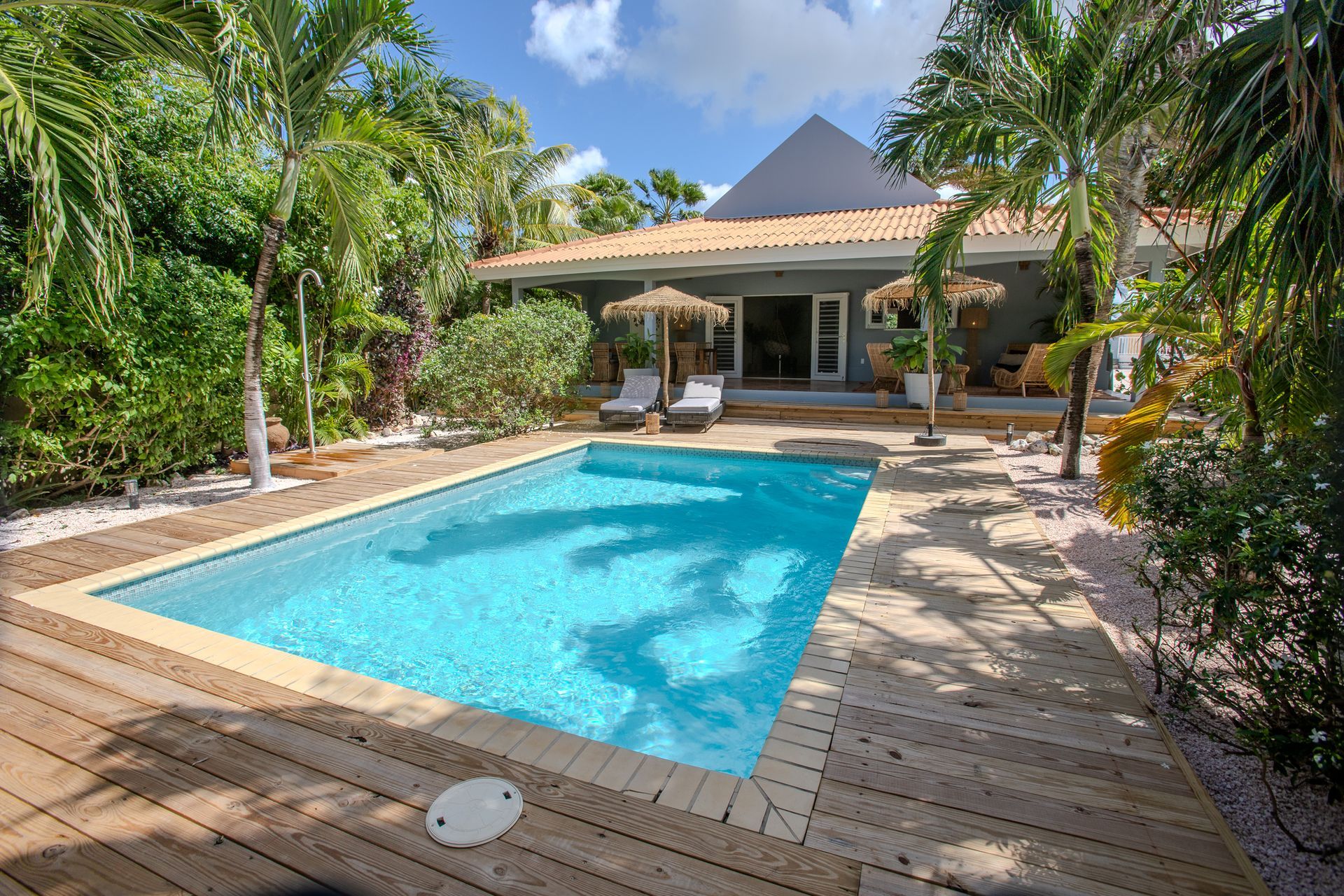 Uitzicht vanaf het zwembad op een huis met een zwembad, een houten terras