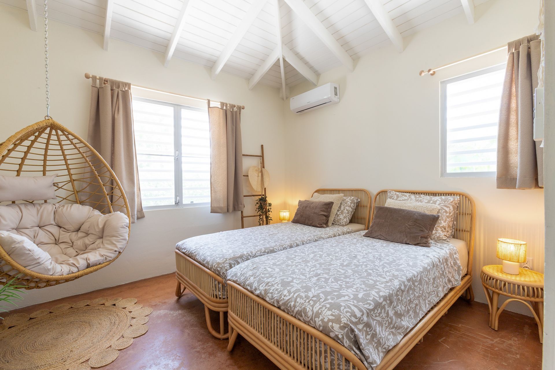 Slaapkamer met twee eenpersoonsbedden, een hangstoel en een klein bijzettafeltje.