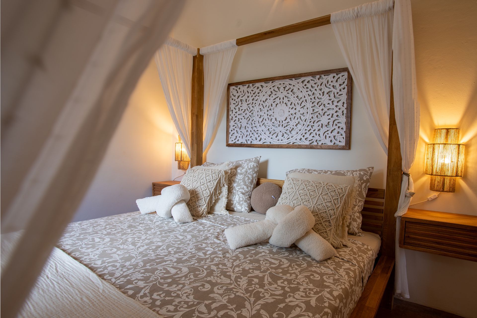 Gezellige slaapkamer met hemelbed, sierkussens en warme verlichting.