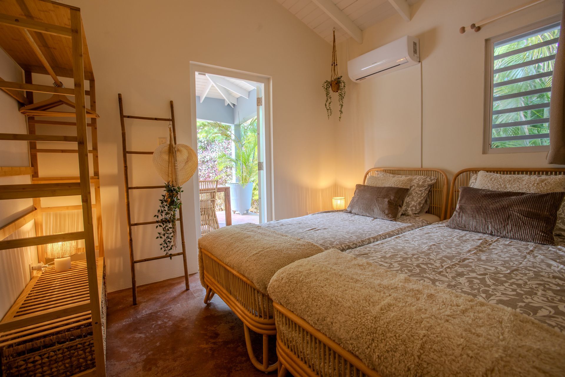 Slaapkamer met twee eenpersoonsbedden, een ladder, een openslaande deur naar de veranda en houten planken.