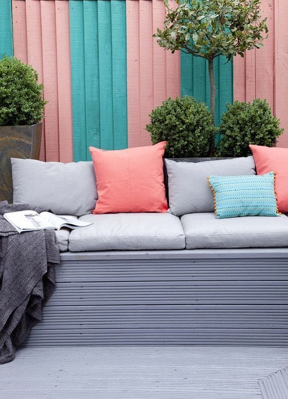 A backyard with chairs and blue and pink painted fence