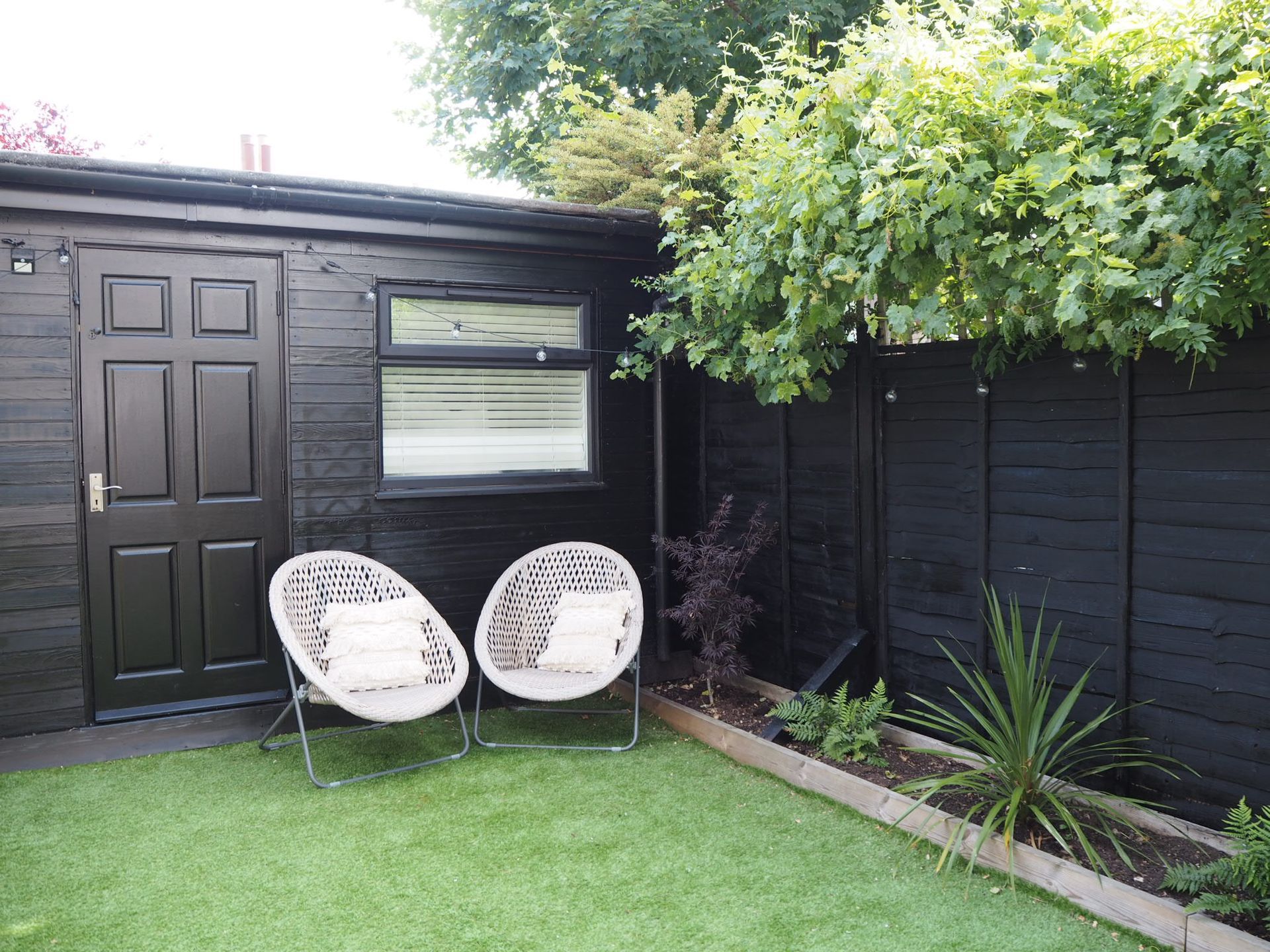 Dark black painted shed in a Sunderland garden in the UK. Expertly painted by Foxglove Decor.