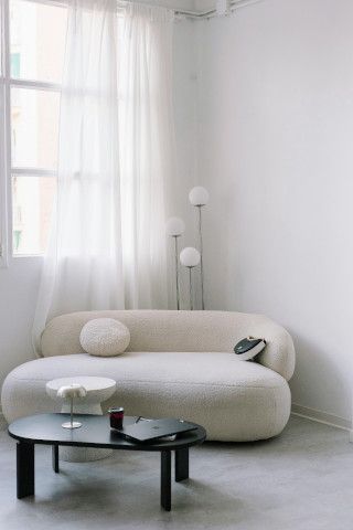 Bathtub and studio couch near a tub, washbasin, and shower curtain.