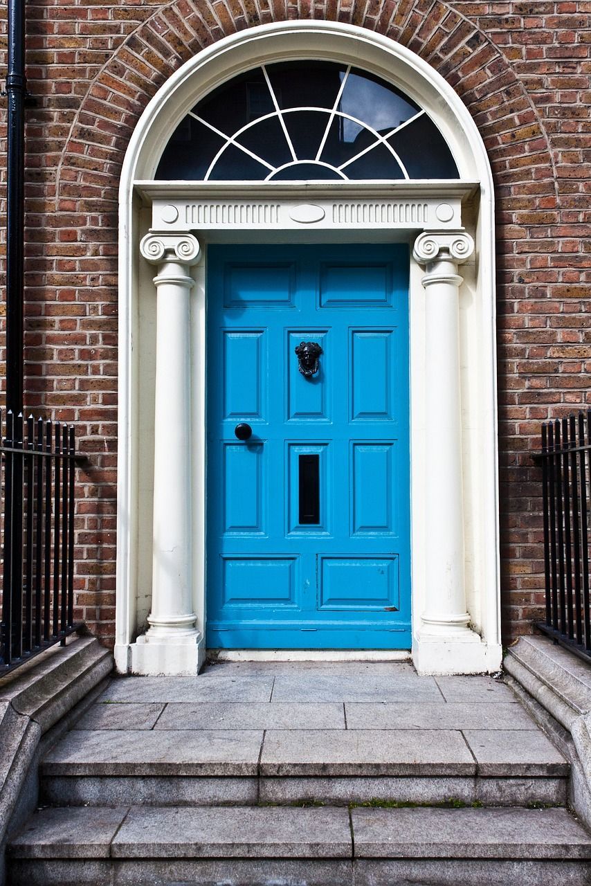 A blue door on a brick building with steps leading up to it in Sunderland, UK. Expertly painted by Foxglove Decor.