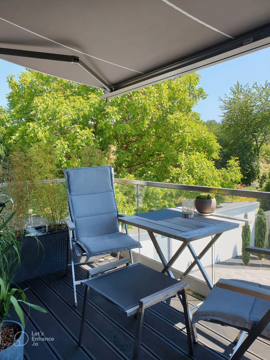 A balcony with a table and chairs under an awning.