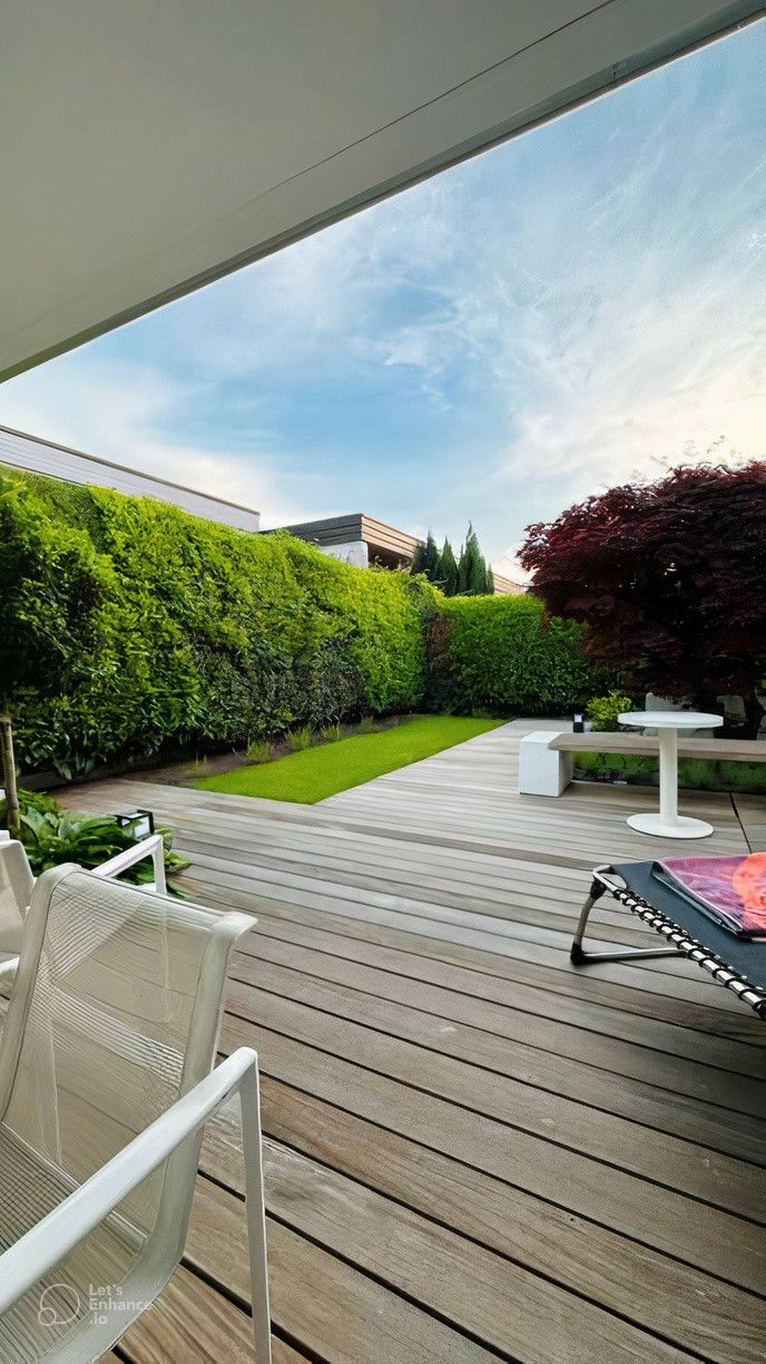 A wooden deck with chairs and a table in a backyard.