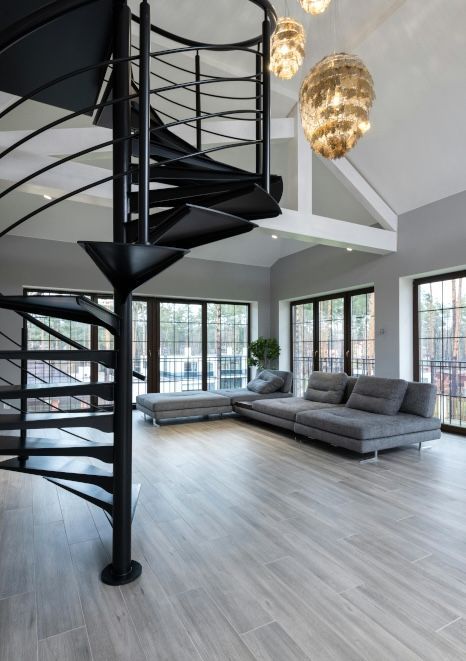 A living room with a spiral staircase and a couch. Staircase expertly painted by Foxglove Decor in Sunderland, UK.