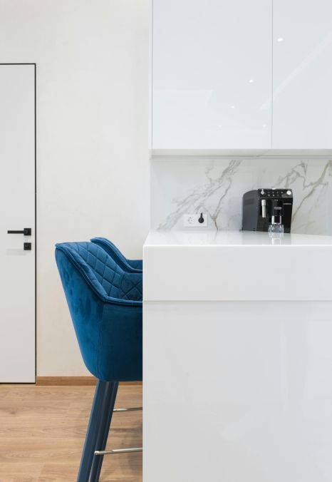 A blue chair is sitting next to a white counter in a kitchen.