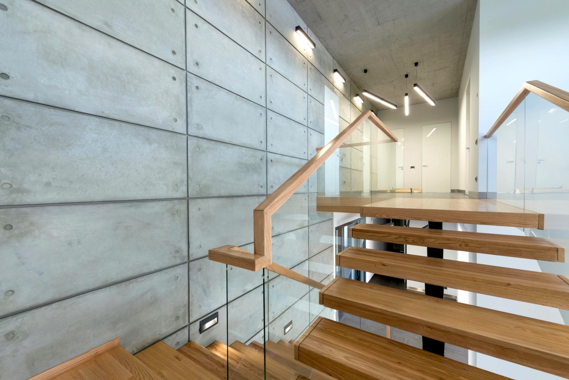 A modern staircase with wooden steps and a glass railing. Staircase expertly varnished by Foxglove Decor in Sunderland.