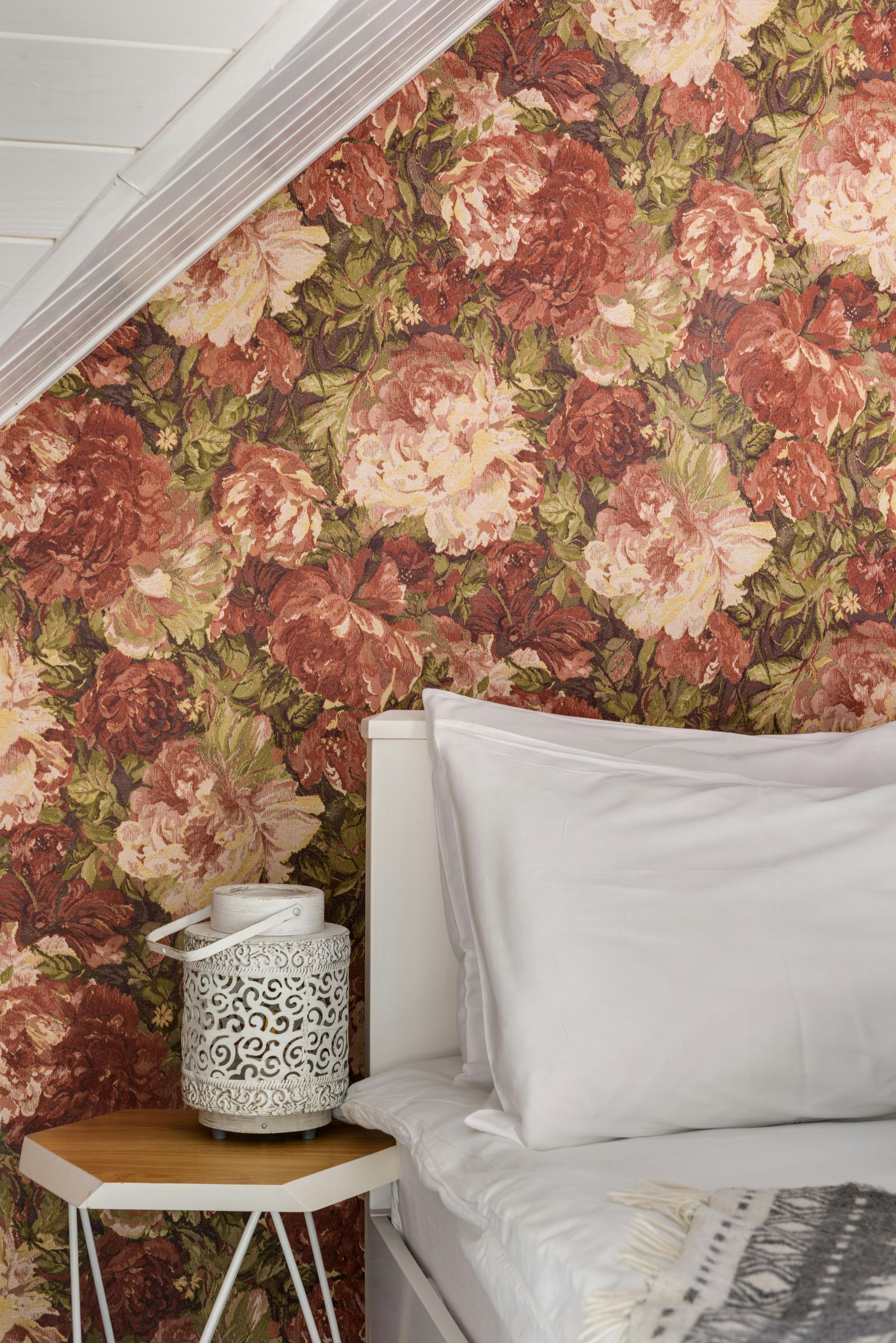 Floral wallpaper with red, white and green soft roses and flowers in a bedroom. Decorated by Foxglove Decor in Sunderland, UK.