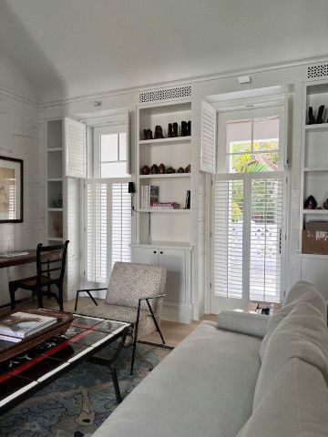 Sliding door leading to a window shade, studio couch, and bookcase in a library.