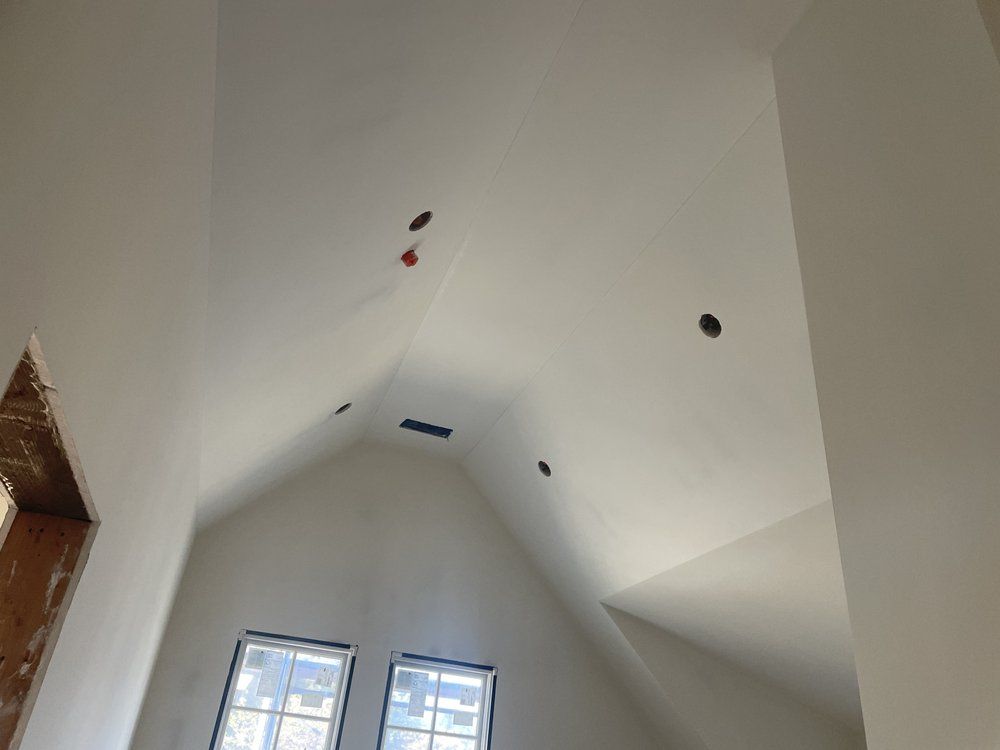 A man is plastering a ceiling with a spatula.
