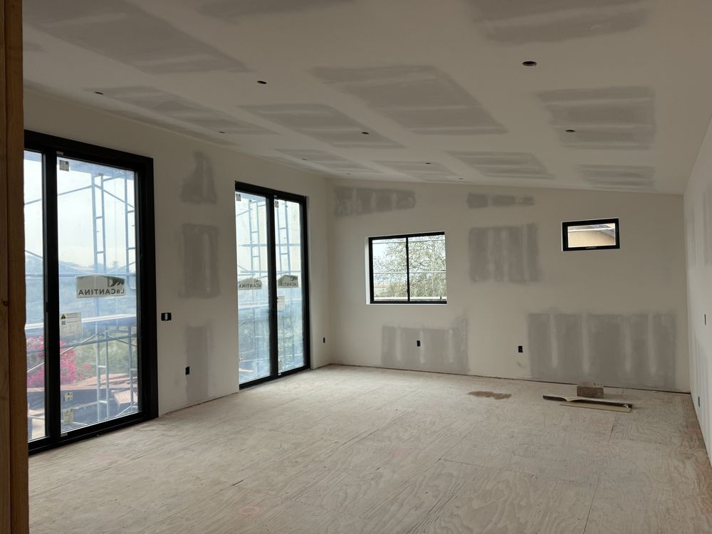 A construction worker is measuring a wall with a tape measure.