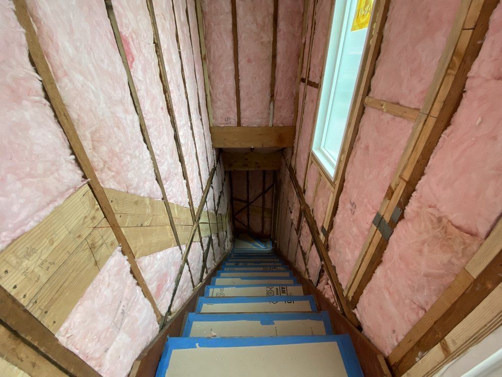 An empty attic with foam insulation and a window.