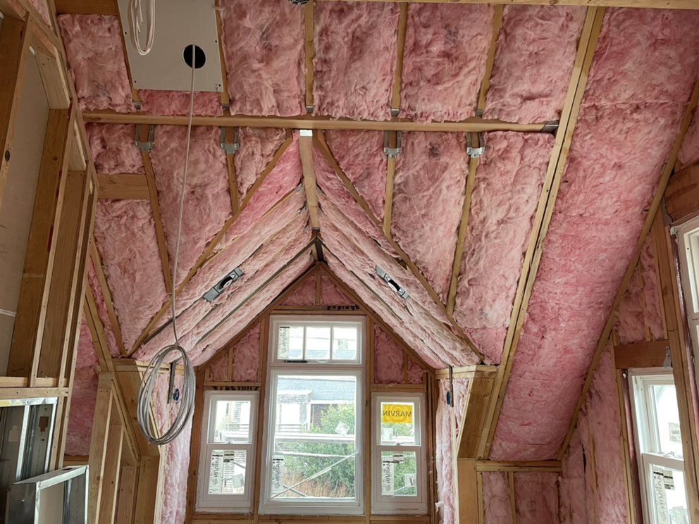 A man is installing insulation on the roof of a house.