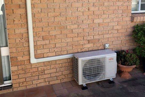 Air Conditioner On Brick Wall — Steve’s Air Conditioning in Shellharbour, NSW