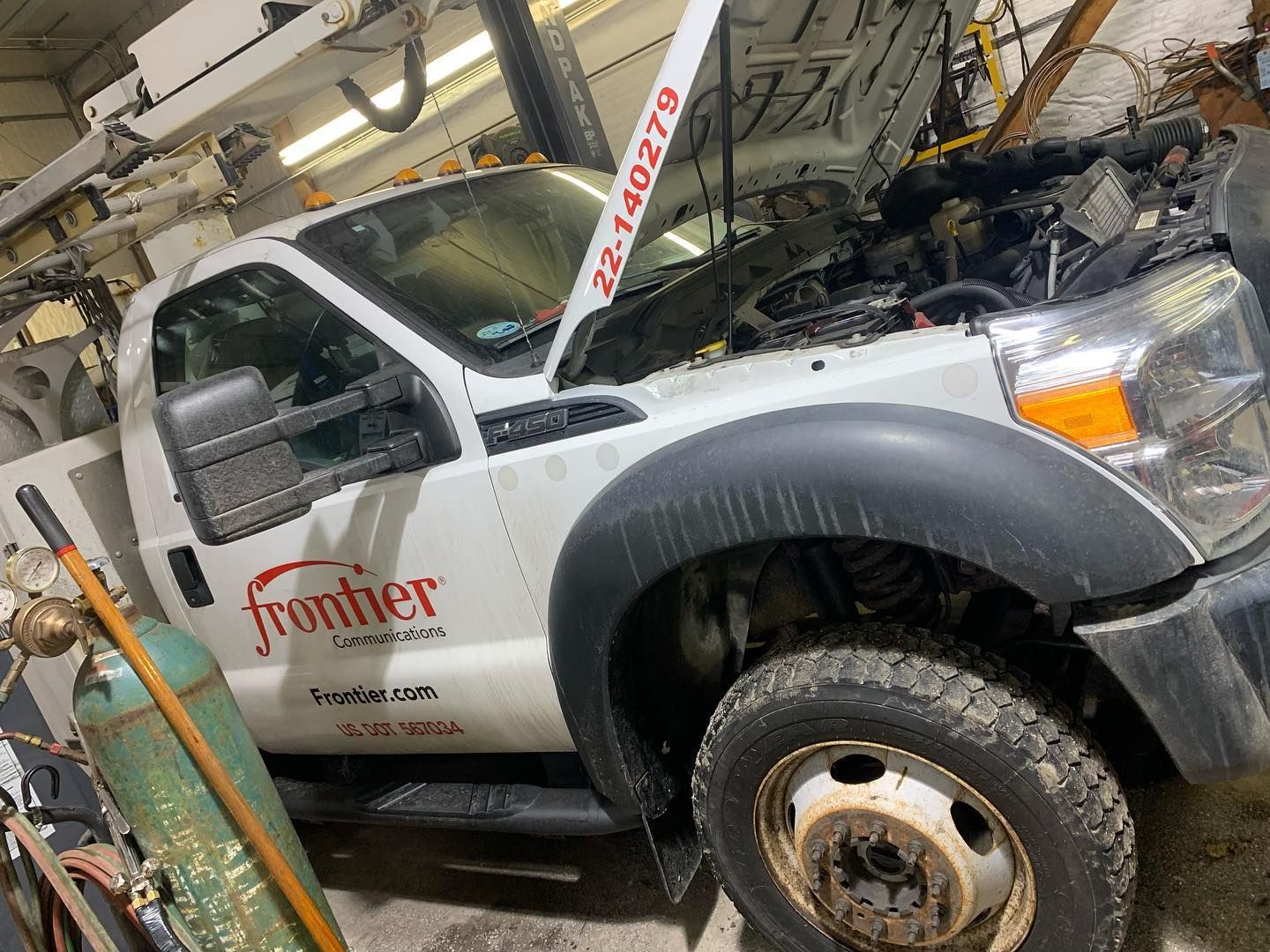 White Frontier truck with the hood open in a garage, next to a welding tank.