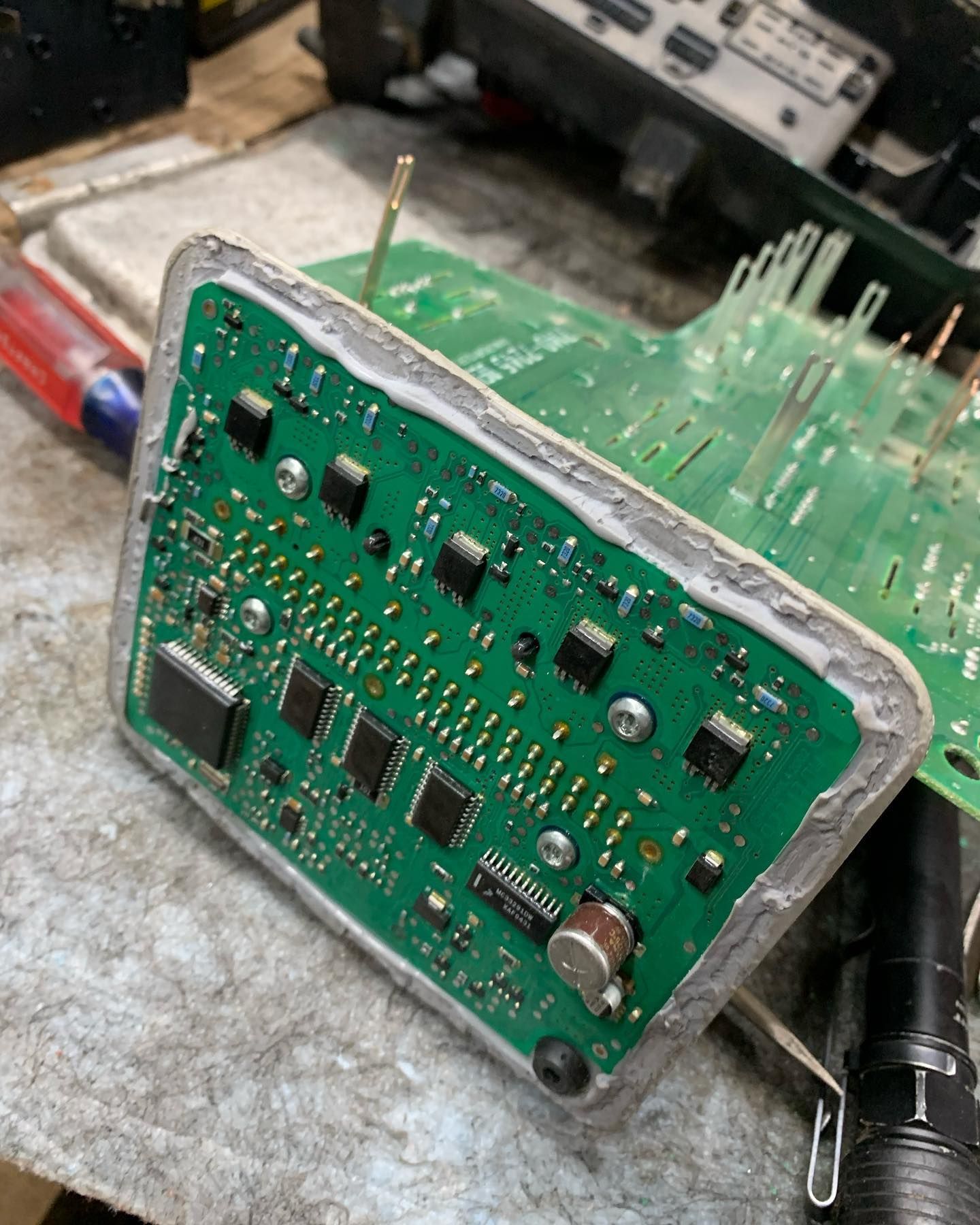 Green circuit board with components and sealant.